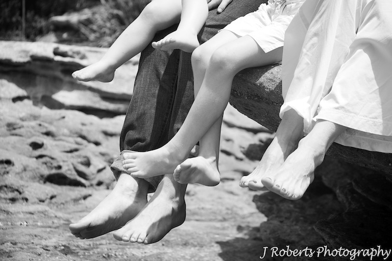 Family legs dangling from the rocks at the beach - family portrait photography sydney